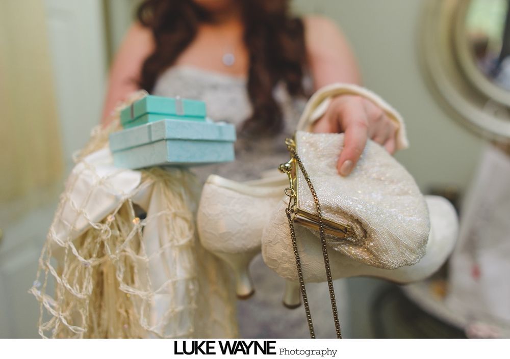 Bride in a white dress, surrounded by bridesmaids in turquoise dresses, smiling in a room.