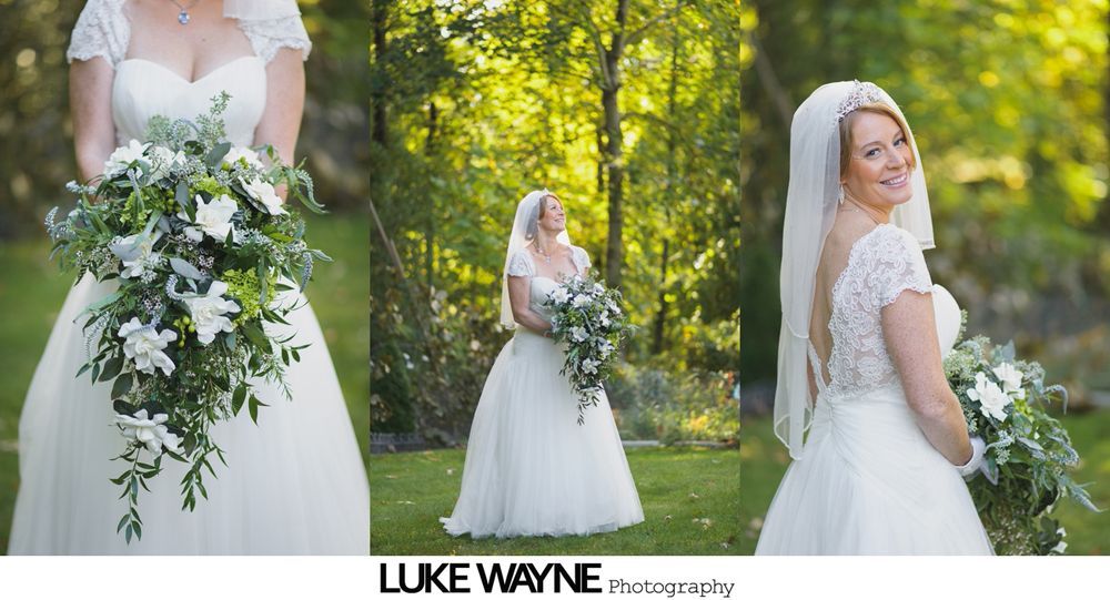 Groom in a suit stands between two brides in dresses in a field with trees, under a blue sky.