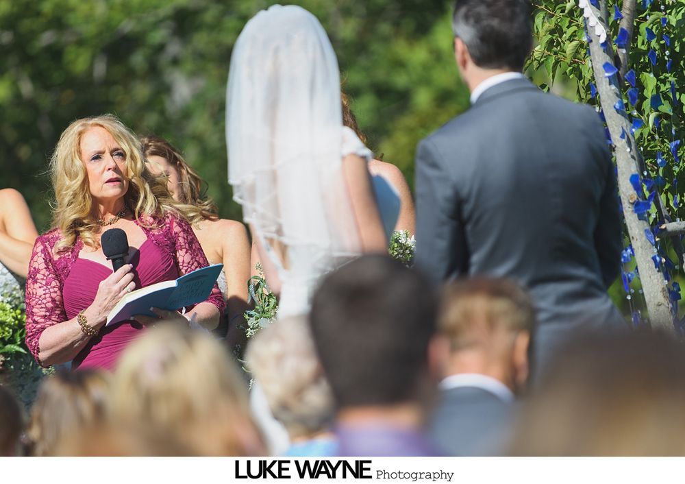 Bride and groom embrace outdoors near a tree with yellow leaves.