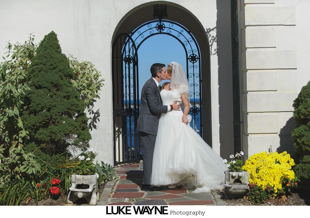 Bride and bridesmaids pose playfully on path. Bride wears white dress and veil; bridesmaids in teal dresses.
