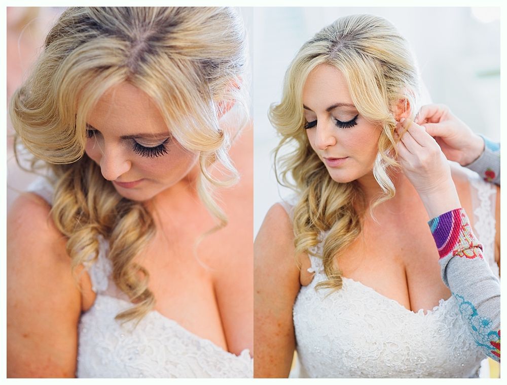 Bride with blonde hair in a white dress getting her earring adjusted; indoor setting.