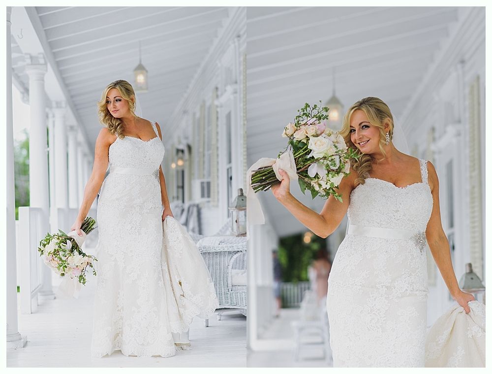 Bride in a white beaded wedding dress with a bouquet, standing on a white porch.