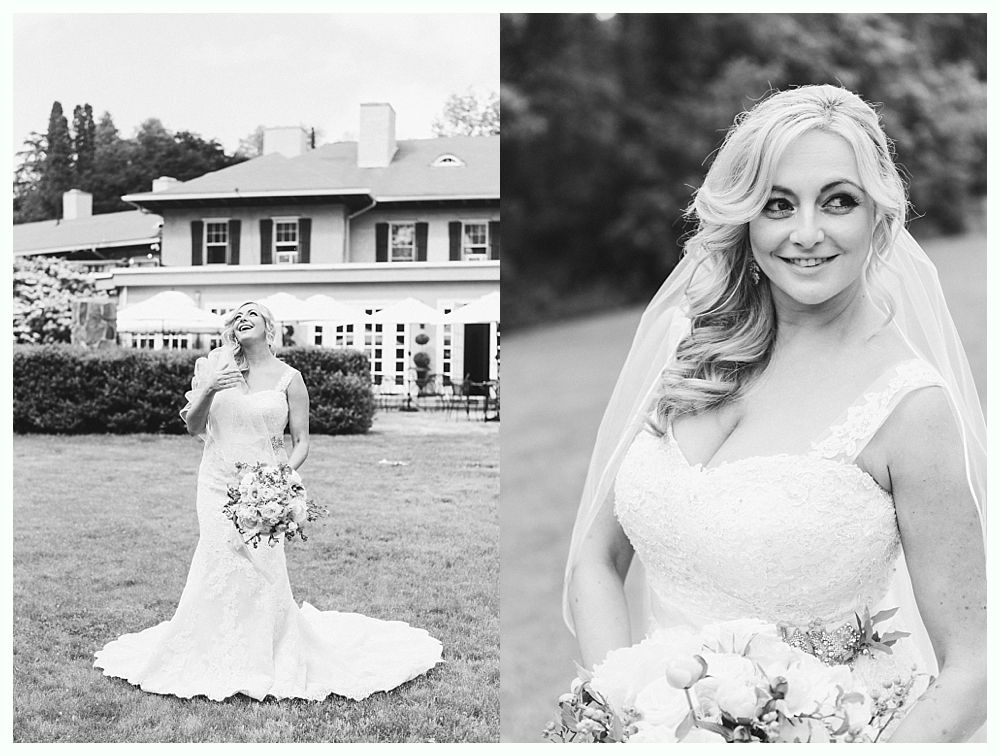Bride in a lace wedding dress, holding bouquet, in front of a building. Black and white.