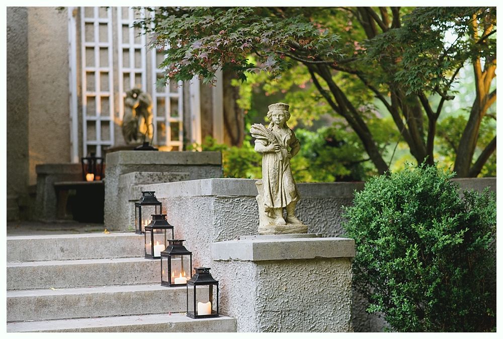 Stone steps and porch with lanterns, statues, and greenery.