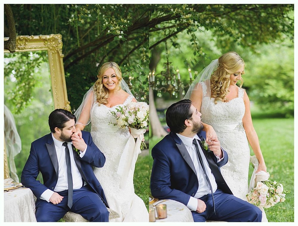Bride and groom pose outdoors. The bride touches the groom's face. They are smiling.
