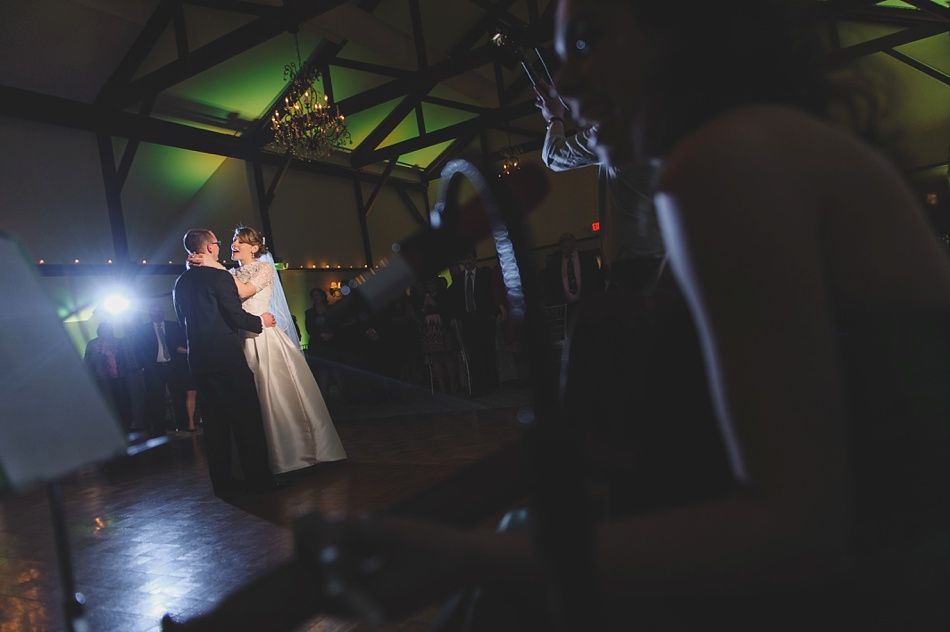 Bride and groom share a dance in a dimly lit hall, seen from the perspective of a musician in the foreground.