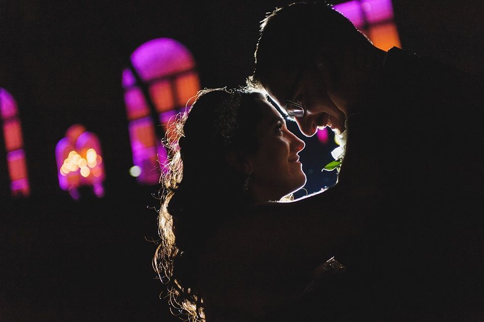 Couple in silhouette embracing, with a purple-lit window backdrop.