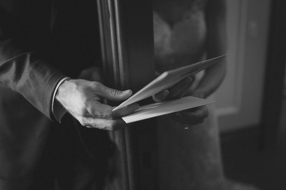 Man holding cards or letters, woman in the background, grayscale.