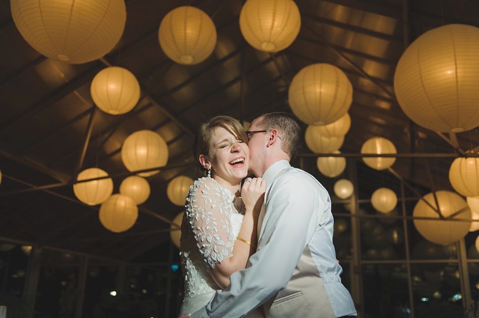 Couple laughing while embraced under paper lanterns.