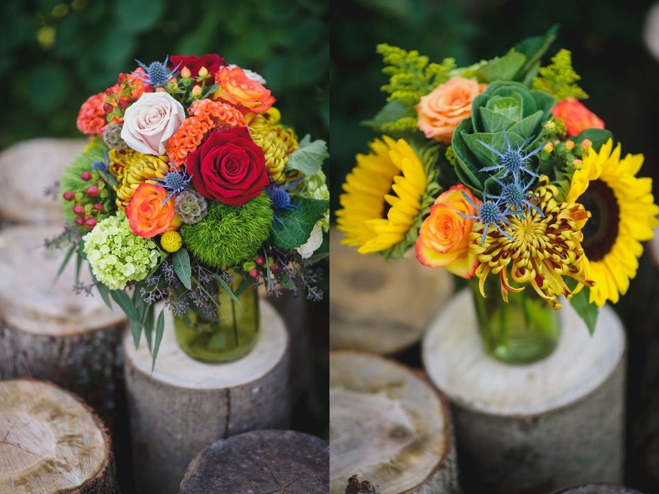 Two vibrant floral arrangements in glass jars on wooden stumps.