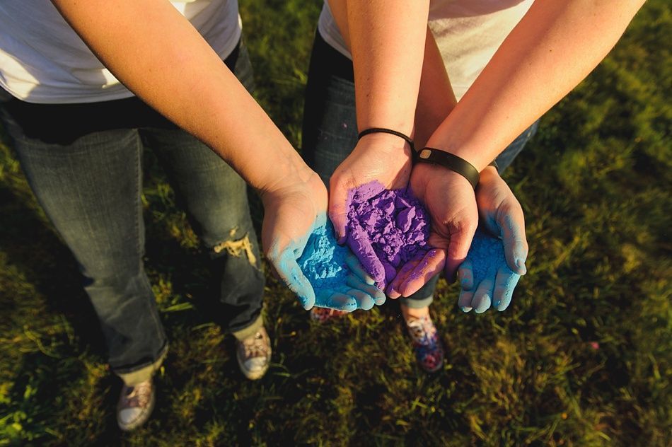 Hands holding blue and purple colored powder outdoors.