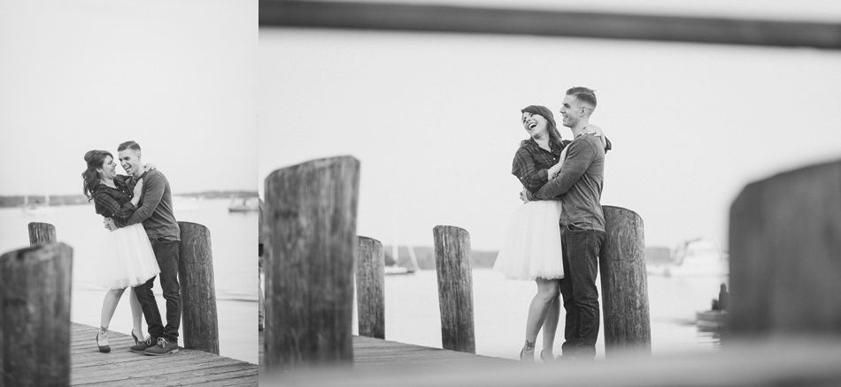 Couple embracing on a wooden pier, laughing. Black and white photo.
