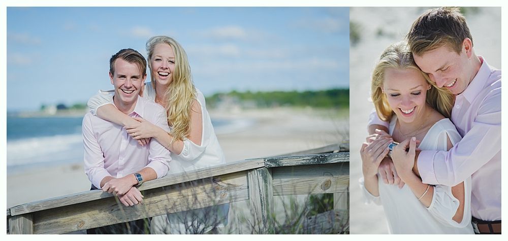 Couple embracing on a beach, smiling; man in pink shirt, woman in white, wooden railing, sunny day.