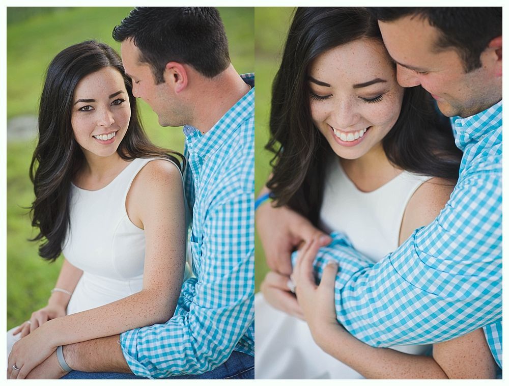 Couple embracing, smiling. Woman in white dress, man in blue plaid shirt. Outdoor setting with green background.