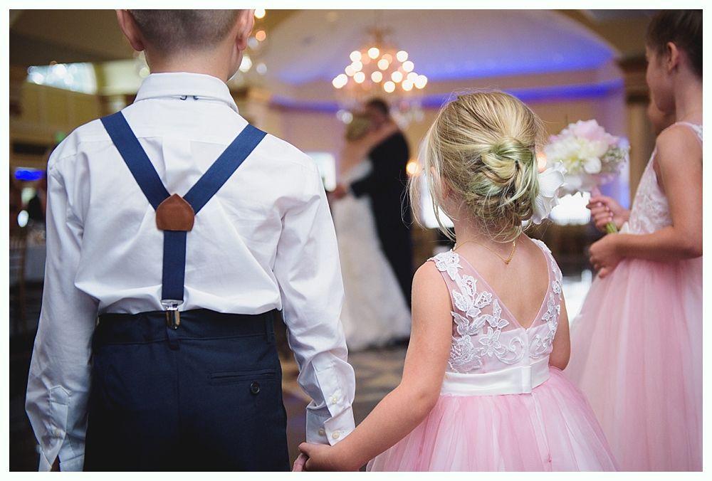 Two children in formal wear watch a wedding couple dancing.