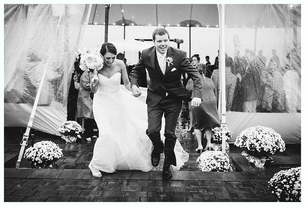 Newly married couple runs out of wedding ceremony, smiling. Black and white photo.