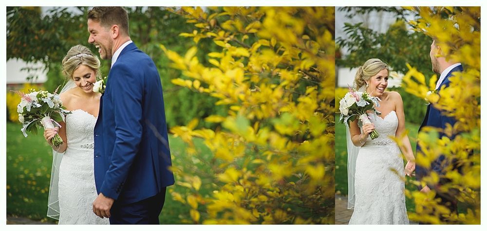 Bride and groom laughing, holding bouquets, by yellow foliage. Wedding setting.