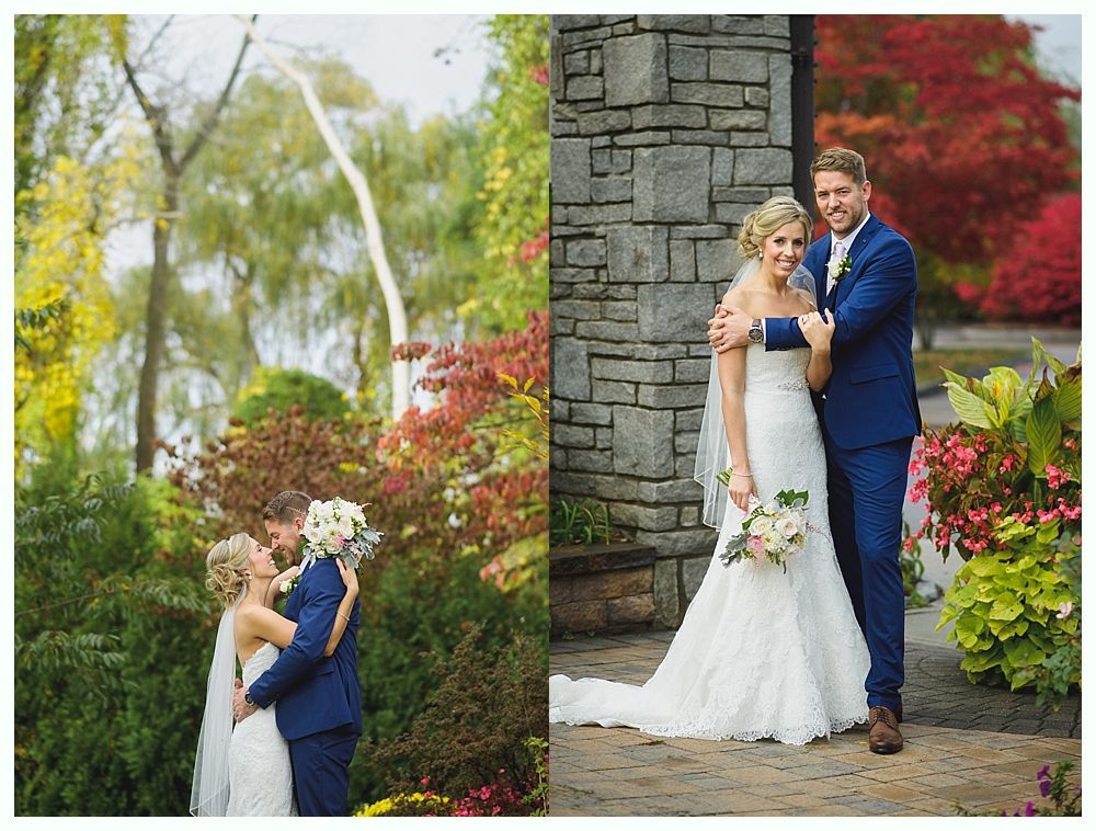 Couple in wedding attire embrace and pose outdoors in a garden setting.