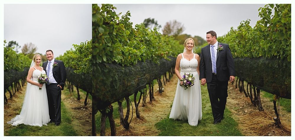 A newlywed couple walking through a vineyard, both smiling. The bride wears a white dress and holds a bouquet.