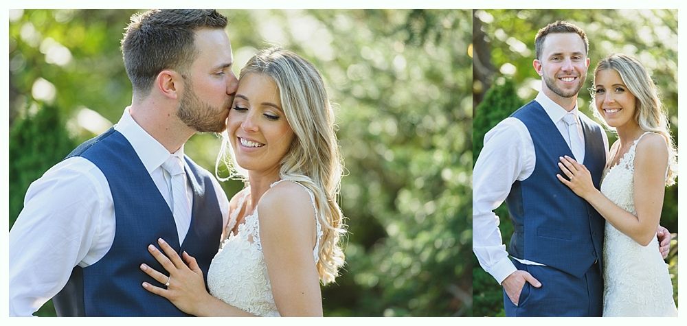 A newlywed couple in formal wear pose outside, the groom kissing the bride's forehead.