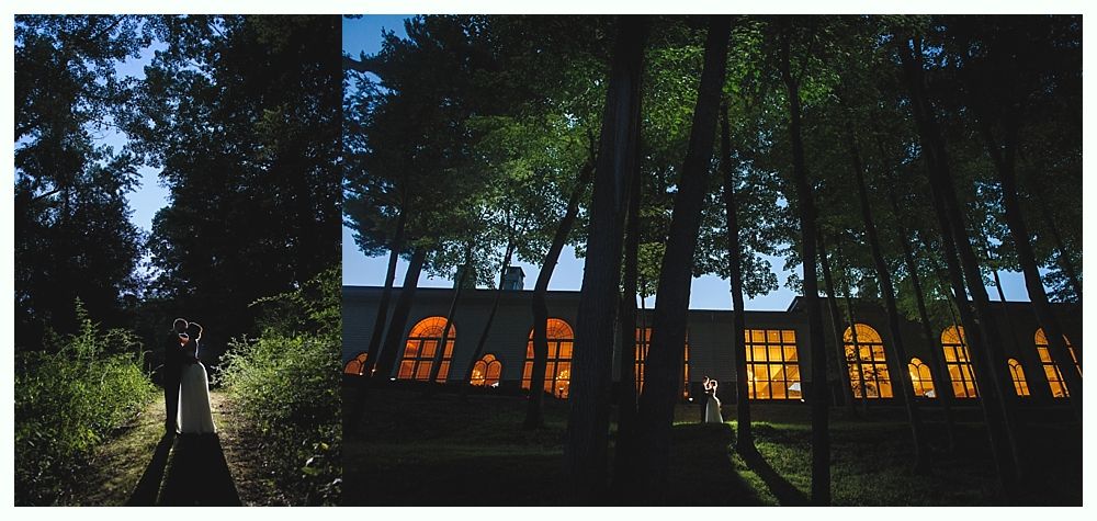 Trees frame a path and a building with lit windows at dusk.