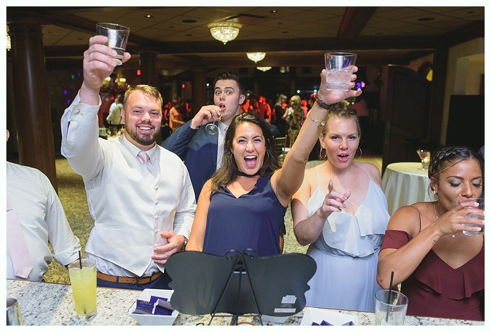 People toasting with drinks at a celebratory event, bar setting.