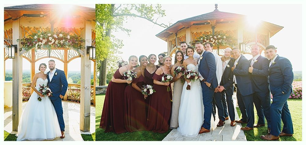 Wedding party under a gazebo; bride and groom with bridesmaids in maroon dresses and groomsmen in navy suits.