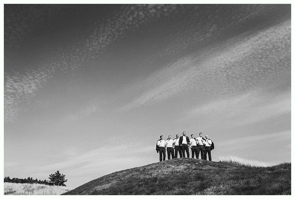 Group of people standing on a hill, under a cloudy sky. Black and white photo.