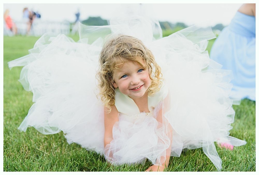 Girl in white tulle dress smiling on grass.