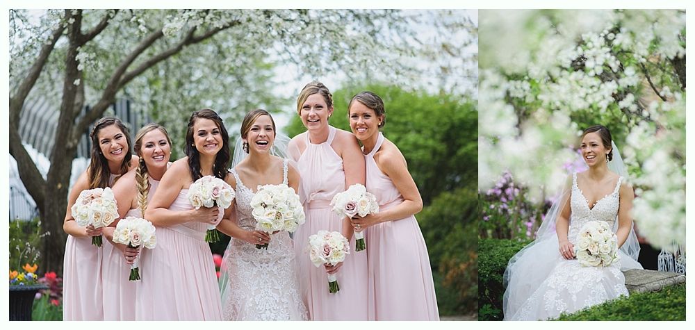 Bride with bridesmaids in pink dresses, holding bouquets, laughing together outdoors.