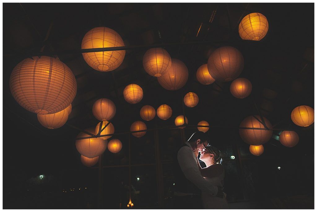 Yellow paper lanterns hang in a darkened space, illuminating a blurry person below.