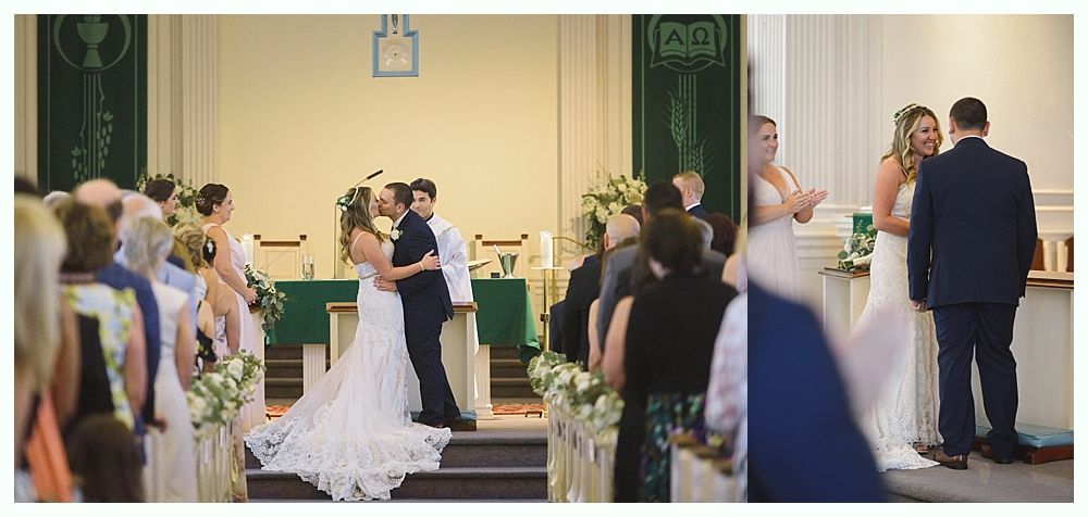 Wedding ceremony in a church; two brides kiss while guests watch.
