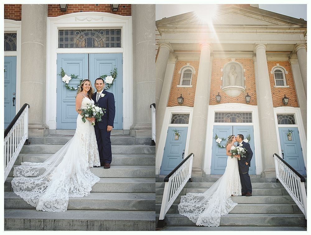 Bride and groom on steps of a church. The bride wears a white dress, the groom a navy suit. They are near blue doors.