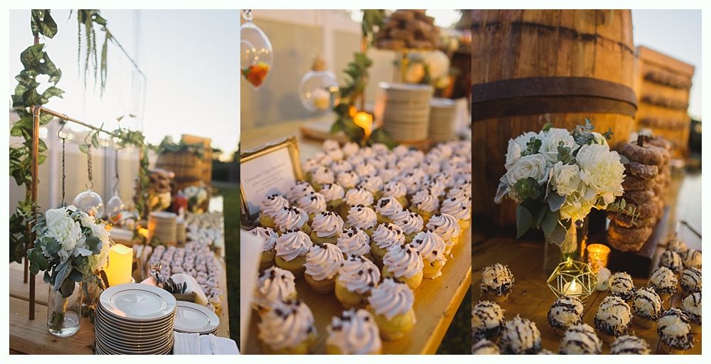 A dessert table at an outdoor event with cupcakes and other treats on wood barrels.