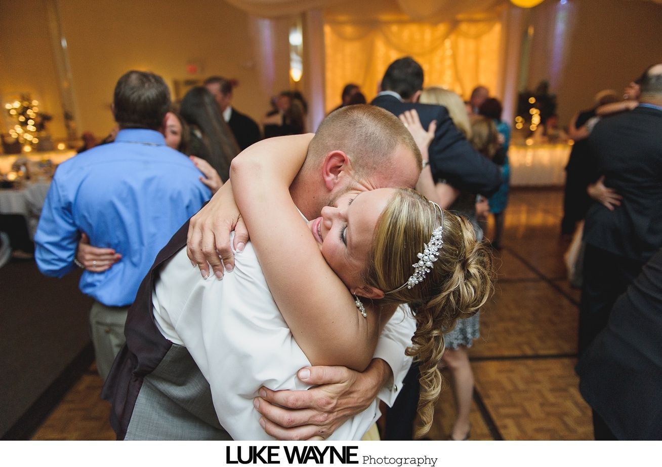 Bride and groom hugging and kissing on a dance floor during a wedding reception.