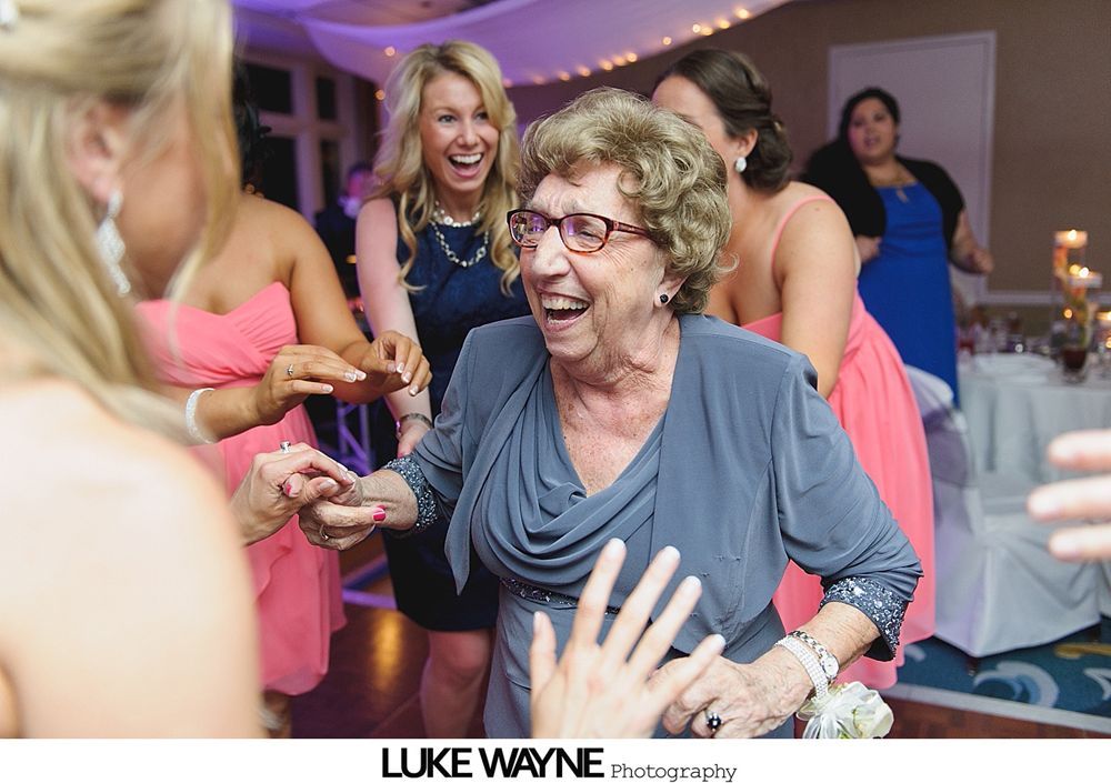 Elderly woman dances at a wedding, surrounded by smiling guests.