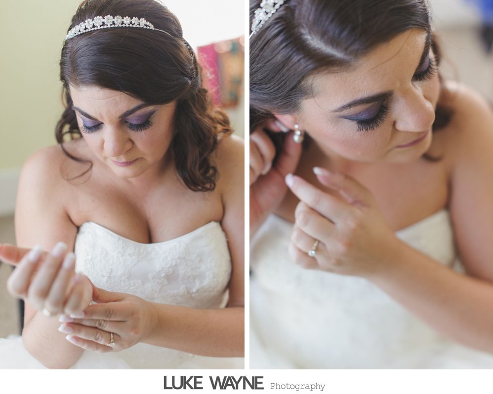 Bride adjusts her jewelry, wearing a strapless wedding dress, a tiara, and purple eyeshadow.