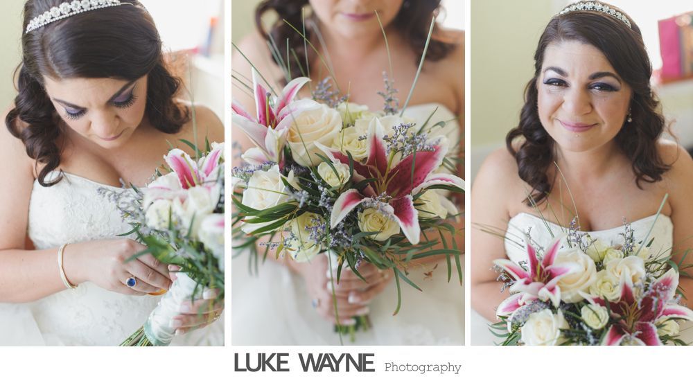 Bride in white dress, holding bouquet with lilies, looks down, center and smiles.