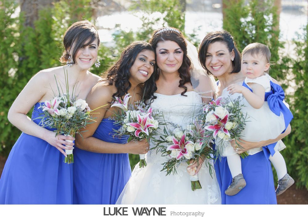 Bride and bridesmaids in blue dresses, holding bouquets, with a child in white dress.