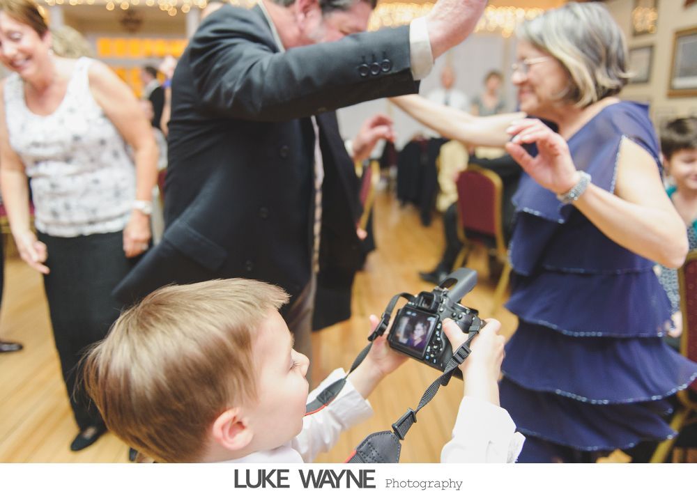 Child using a camera, photographing people dancing at a party.