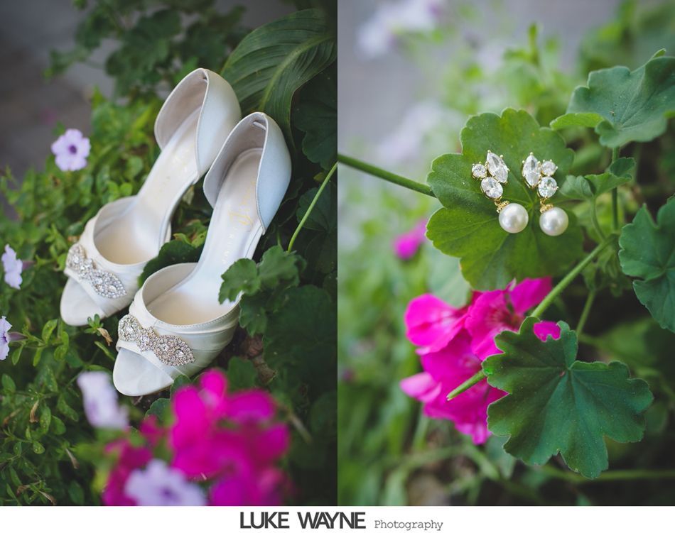 Wedding shoes and earrings on leaves, with pink and purple flowers.
