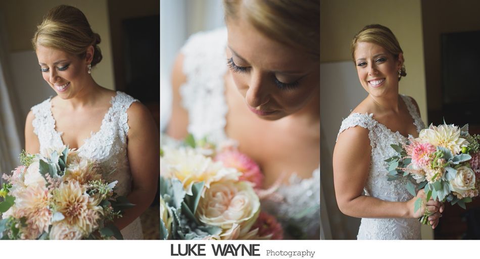 Bride in white lace dress holds a bouquet, smiling. Indoor, natural light.