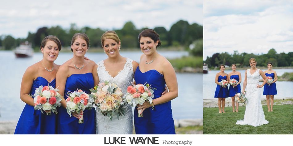 Bride and bridesmaids in blue dresses pose by a lake.