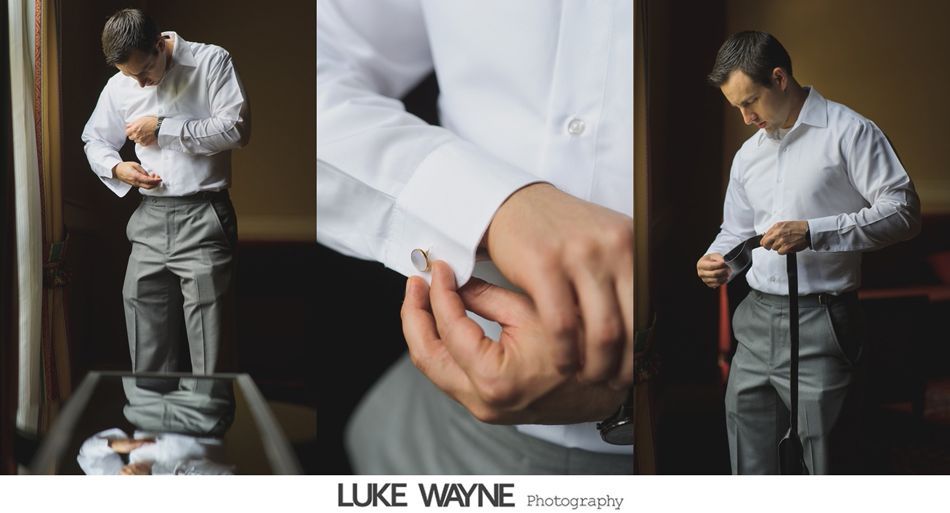 Man adjusting shirt, putting on cufflinks, and preparing tie. Light-colored shirt and gray pants.