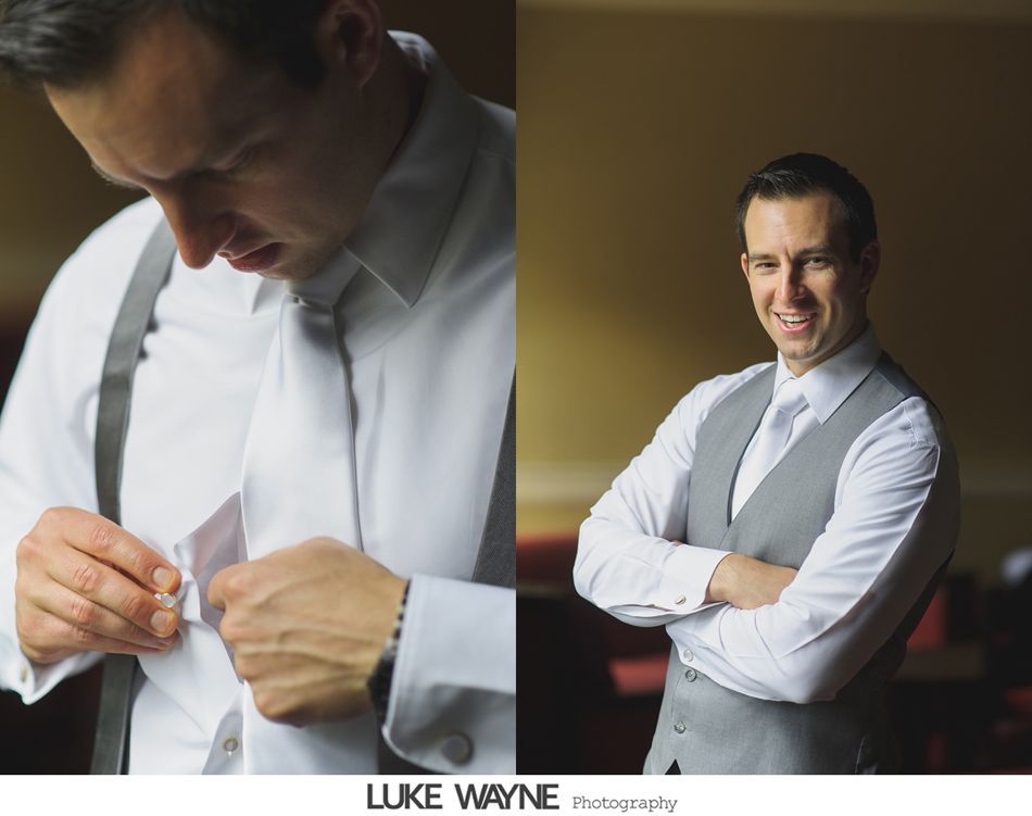 Man in white shirt and grey vest adjusting cufflink, smiling in a well-lit room.