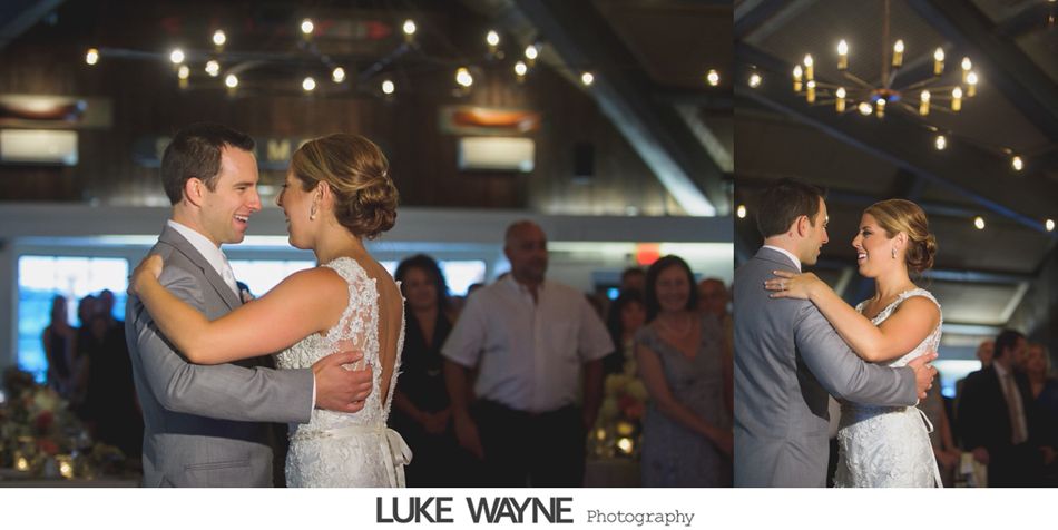 Couple dances at a wedding reception under string lights; a chandelier is in the background.