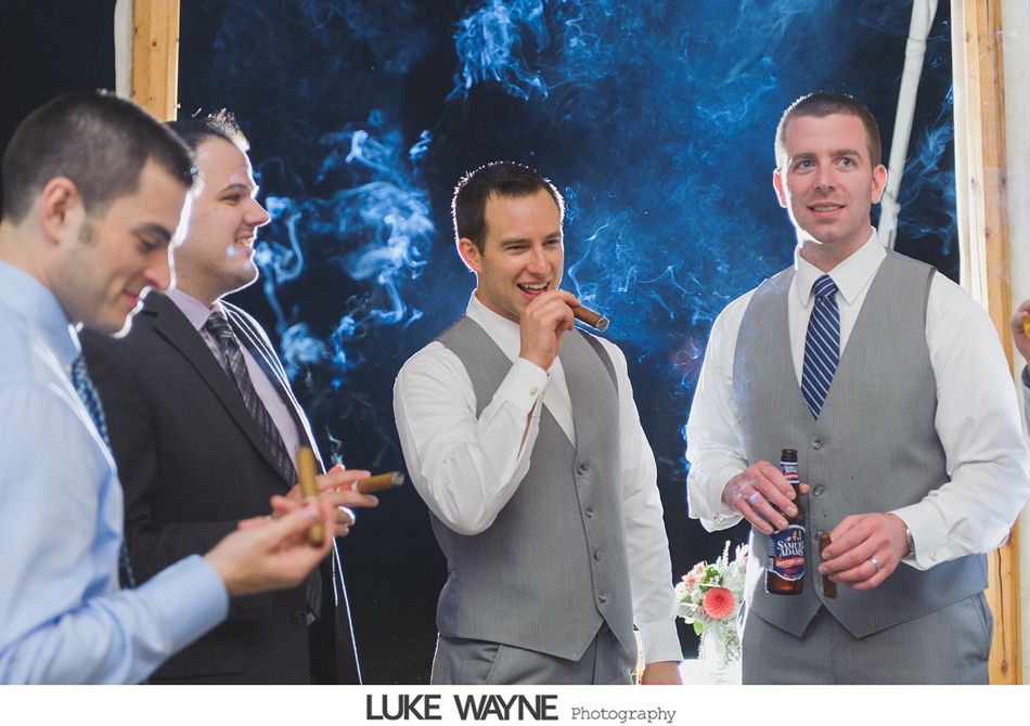 Four men in formal wear, smoking cigars and drinking. Smoke fills the air.