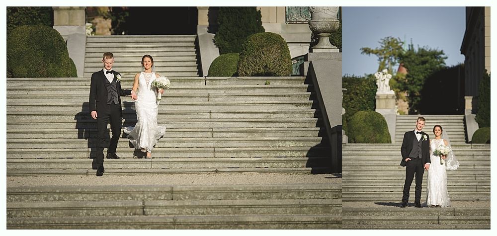 Wedding couple descending stone steps, posing for photos. Bride in white dress, groom in tuxedo.