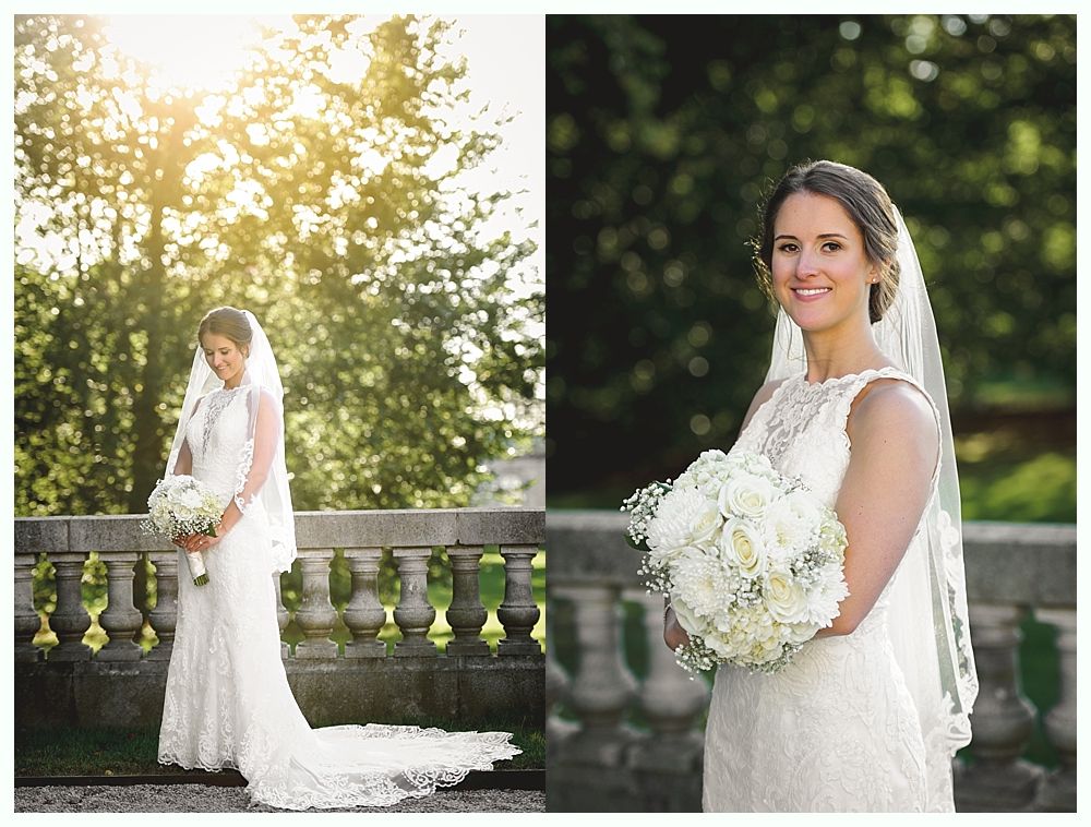 Bride in lace wedding dress, holding bouquet, on a stone balcony with a veil.