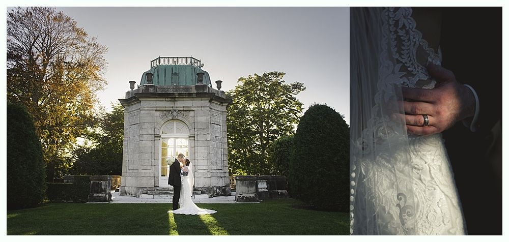 Wedding couple kissing in front of a stone structure, groom's hand on bride's back.